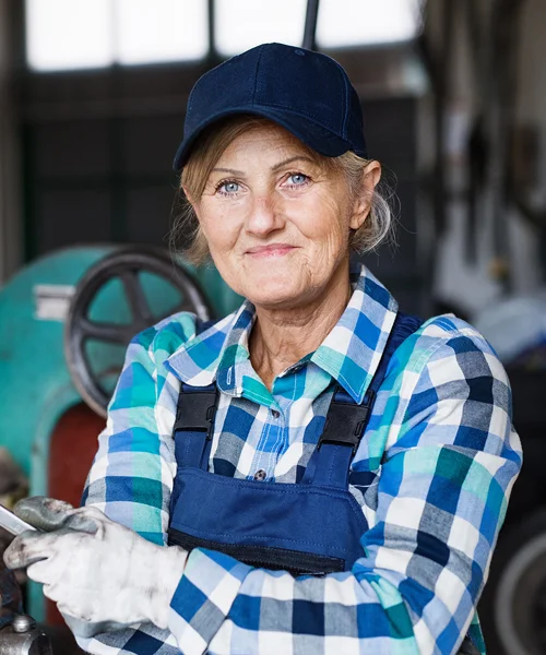 An elderly female mechanic in work attire