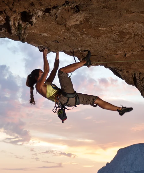A female rock climber hanging upside down on a cliff face