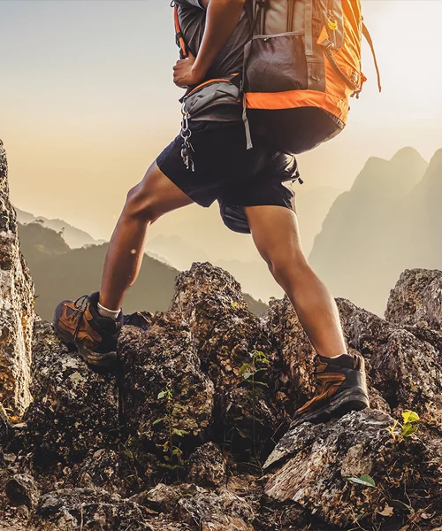 A man hiker carrying a backpack and hiking through rocky mountains